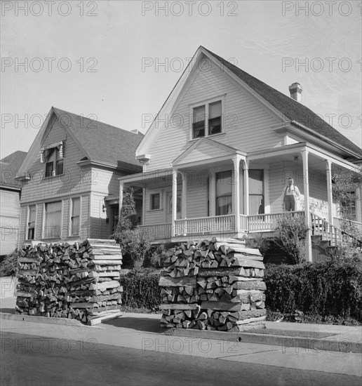 Woodpiles along the street are a characteristic of Portland, Oregon, 1939. Creator: Dorothea Lange.