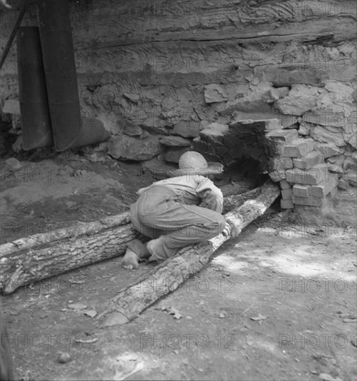 Ten year old son of tobacco tenant tends the fire..., Granville County, North Carolina, 1939. Creator: Dorothea Lange.