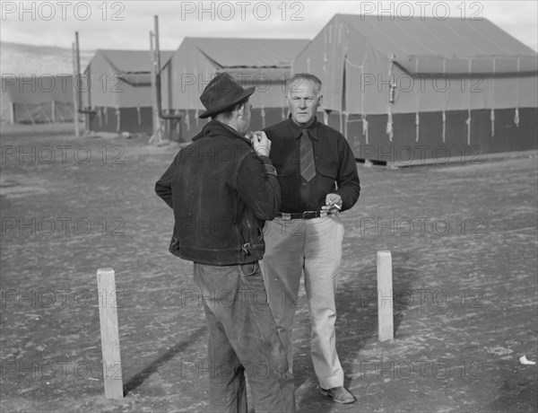 Camp manager talking to another man, FSA mobile camp, Merrill, Klamath County, Oregon, 1939. Creator: Dorothea Lange.