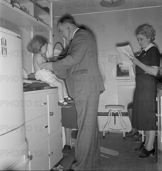 Doctor examining children in trailer clinic, FSA mobile camp, Klamath County, Oregon, 1939 Creator: Dorothea Lange.