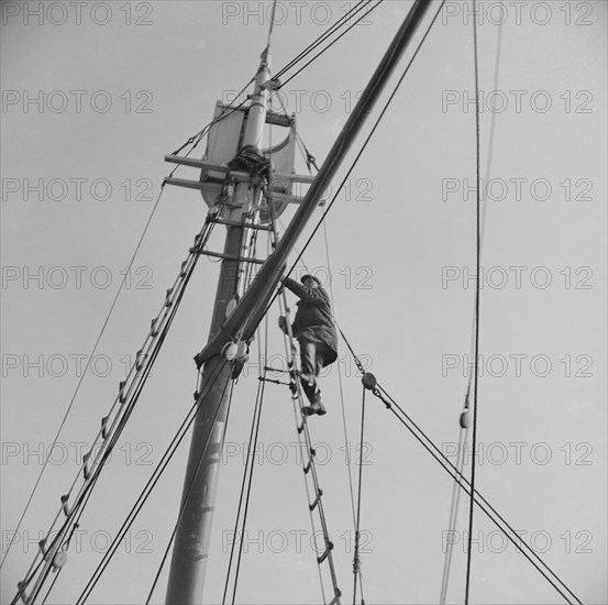 Frank Mineo, owner of the Alden, climbs to the crow's nest..., Gloucester, Massachusetts, 1943. Creator: Gordon Parks.