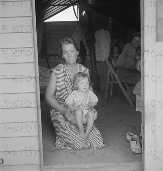 Migrant mother and child at doorway of steel shelter, FSA camp, Tulare County, 1939. Creator: Dorothea Lange.