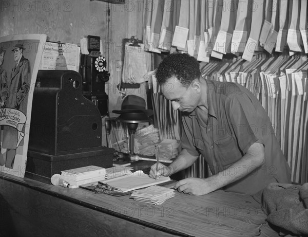 A tailor in Frank's cleaning and pressing establishment checking..., Washington, D.C., 1942. Creator: Gordon Parks.