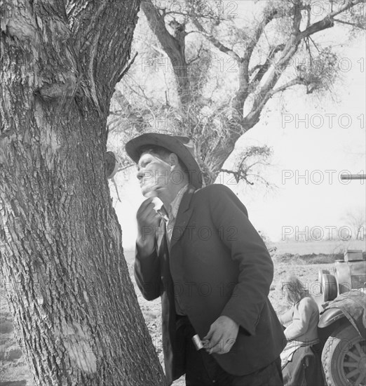 Migrant man shaving by roadside, on U.S. 99 between Bakersfield and the Ridge, 1939. Creator: Dorothea Lange.