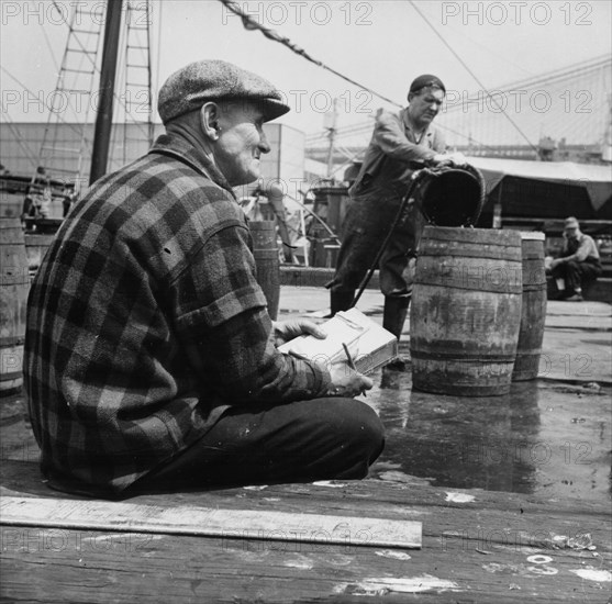 New England fisherman checking baskets of fish as they are lifted from his ship, New York, 1943. Creator: Gordon Parks.