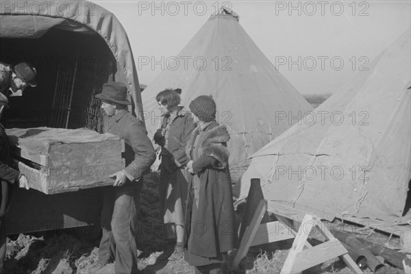 Unloading household goods of a family of white flood refugees in camp at Forrest City, Arkansas.