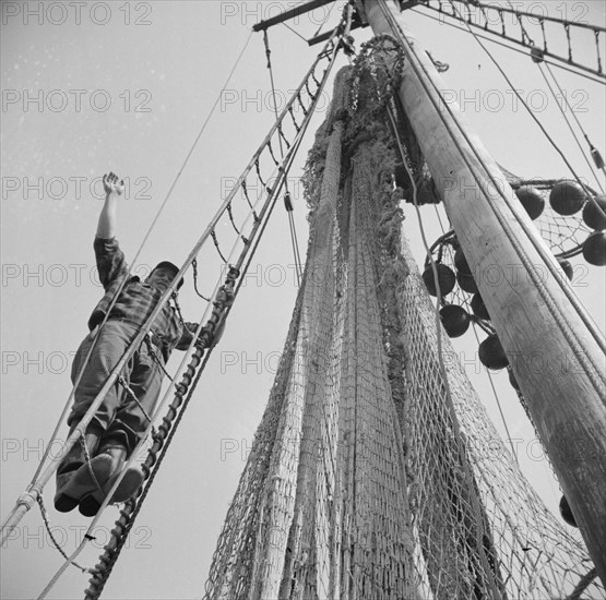 New York, New York. Gloucester fisherman standing in the rigging of a New England fishing boat.