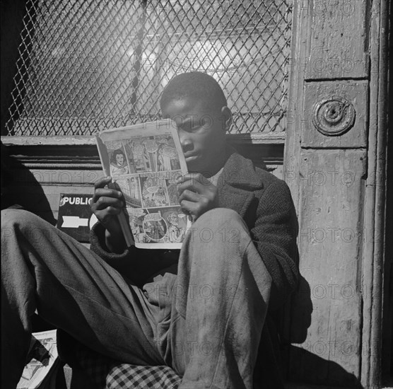 Washington, D.C. Negro youth reading a funny paper on a door step in the Southwest section.