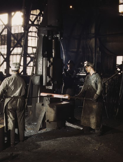 Working with a small steam drop hammer, blacksmith shop, Santa Fe RR shops, Topeka, Kansas, 1943. Creator: Jack Delano.