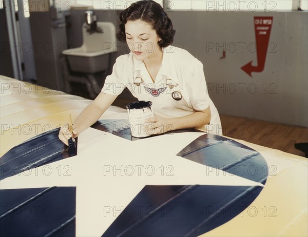 Painting the American insignia on airplane wings is a job that Mrs..., Corpus Christi, Texas, 1942. Creator: Howard Hollem.