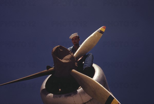 This sailor mechanic is inspecting a PBY plane at the Naval Air Base in Corpus Christi, Texas, 1942. Creator: Howard Hollem.