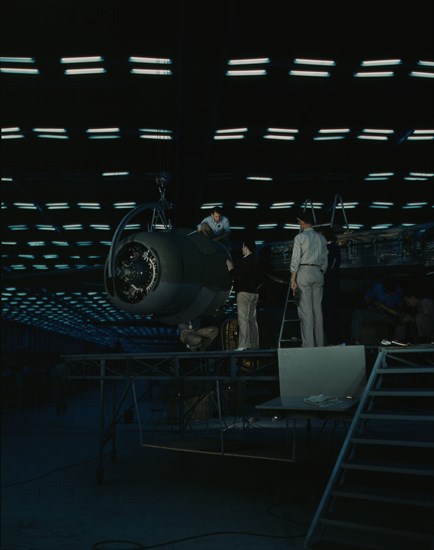 Lowering an engine in place in assembling...Consolidated Aircraft Corp..., Fort Worth, Texas, 1942. Creator: Howard Hollem.