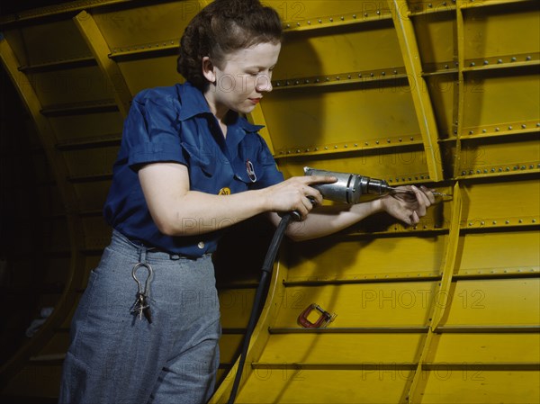 Operating a hand drill at Vultee-Nashville, woman is working on a "Vengeance" dive..., Tenn., 1943. Creator: Alfred T Palmer.