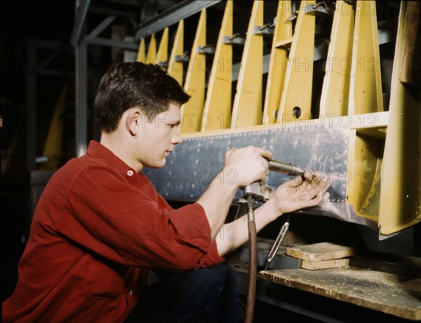 Riveter at work at the Douglas Aircraft Corporation plant in Long Beach, Calif., 1942. Creator: Alfred T Palmer.