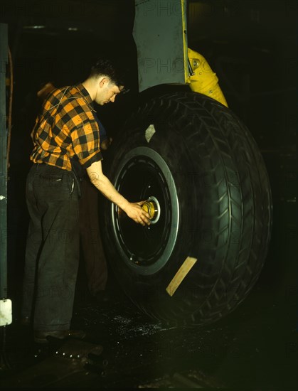 Inspecting of landing wheel of the transport planes at Willow Run, between 1941 and 1945. Creator: Howard Hollem.