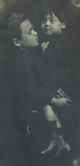 Young boy holding a smaller child, c1900.