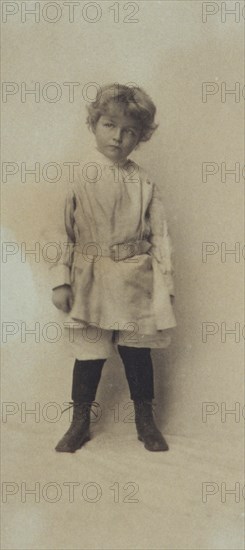 Portrait of a young boy standing in short pants and belted shirt, c1900.