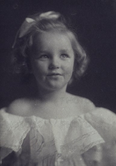 Young girl in a white off-the-shoulder dress with a ribbon in her hair , c1900.