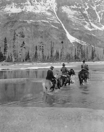 Three campers on horseback cross the Columbia River in Washington, 1903.