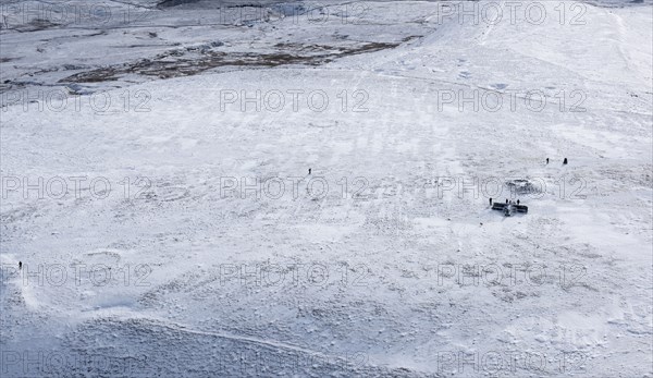 Walkers on a snowy Ingleborough Hillfort, with hut circle earthworks also visible, North Yorkshire, 2018.