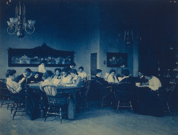 Students seated around tables, studying, at Western High School, Washington, D.C., (1899?).