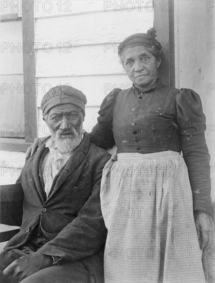Elderly African American couple posed outside of building, near Hampton Institute, Hampton, Va., 1899 or 1900.