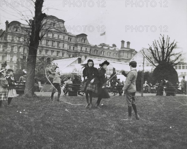 Children jumping rope on the White House lawn during annual Easter egg roll with State, War...1898. Creator: Frances Benjamin Johnston.