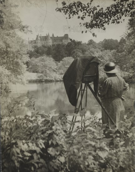 Photographer Frances Benjamin Johnston standing beside her large view camera looking..., c1938. Creator: Unknown.