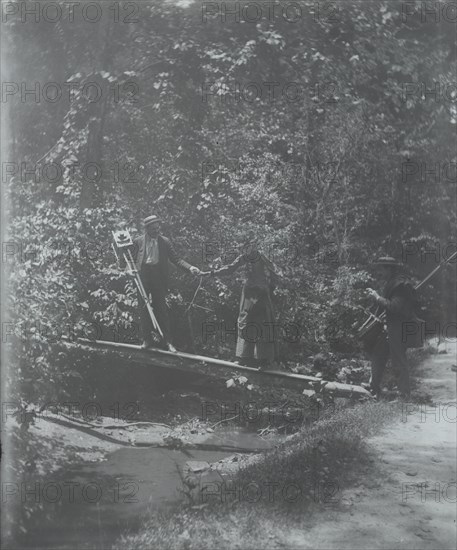 Group crossing footbridge with cameras, between 1885 and 1900. Creator: Frances Benjamin Johnston.