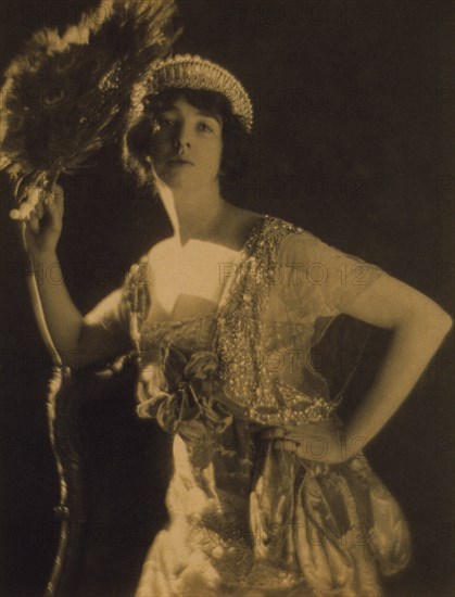 Three-quarter length portrait of Gertrude Vanderbilt Whitney...holding a peacock feather fan, c1916. Creator: Adolph de Meyer.