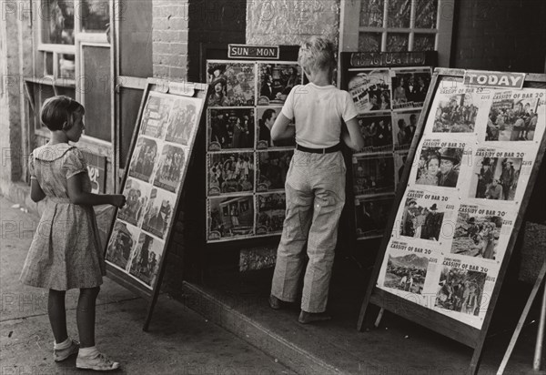 Children looking at posters in front of movie, Saturday, Steele, Missouri, 1938-08.