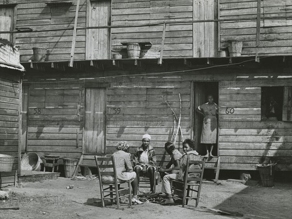 African American woman standing in doorway and African American girls sitting around..., Feb 1941. Creators: Farm Security Administration, Marion Post Wolcott.