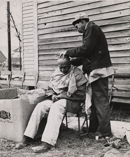 Negro getting a haircut in front of church which houses flood refugees. Sikeston, Missouri, 1937-02.