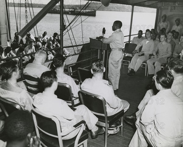 African American chaplain standing at the podium and conducting the religious service..., 1939 - 194 Creator: United States Coast Guard.