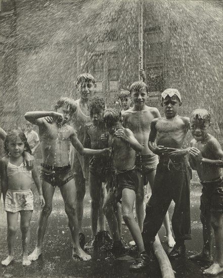 Group of children, mostly boys, gathered under sprinkler, in East Harlem, New York City, 1947 - 1951.