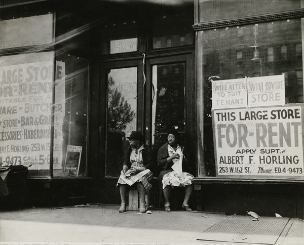 Sidewalk sitters. Two women sitting in doorway of empty storefront that is being..., ca. 1930s. Creator: Unknown.