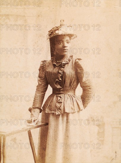 Woman in hat decorated with flowers, and striped blouse, (1900-1950?). Creator: Madison Art Studio.