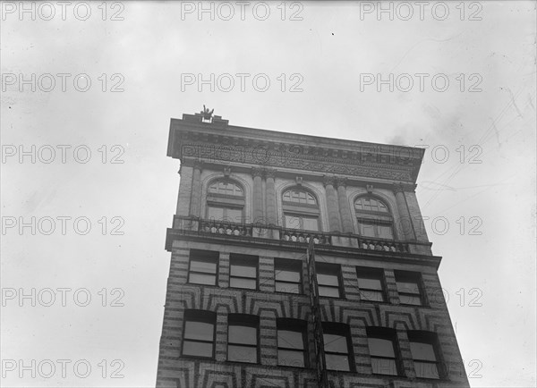 J. Reynolds, Performing Acrobatic And Balancing Acts On High Cornice Above 9th Street, N.W., 1917. Creator: Harris & Ewing.