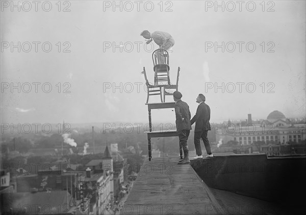 J. Reynolds, Performing Acrobatic And Balancing Acts On High Cornice Above 9th Street, N.W., 1917. Creator: Harris & Ewing.