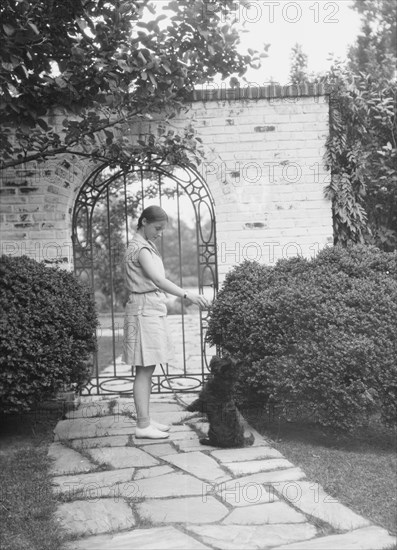 Brady, Genevieve, Miss, with dog, standing outdoors, between 1928 and 1931. Creator: Arnold Genthe.