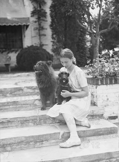 Brady, Genevieve, Miss, with dogs, seated outdoors, between 1931 and 1934. Creator: Arnold Genthe.