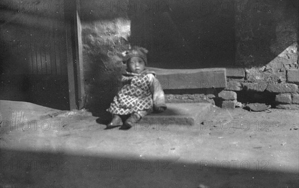 Small child sitting on a doorstep, Chinatown, San Francisco, between 1896 and 1906. Creator: Arnold Genthe.