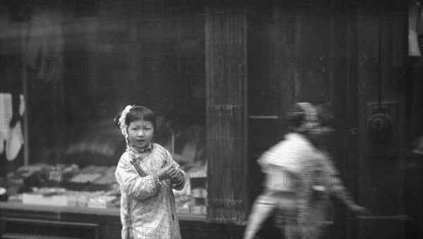 Young girl walking down the street, looking into the camera, Chinatown, San Francisco, c1896-1906. Creator: Arnold Genthe.