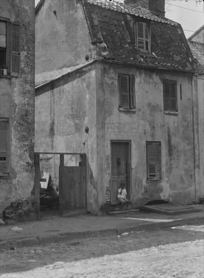 Boy sitting in the doorway of a two-story building, [17 Chalmers Street], Charleston..., c1920-c1926 Creator: Arnold Genthe.