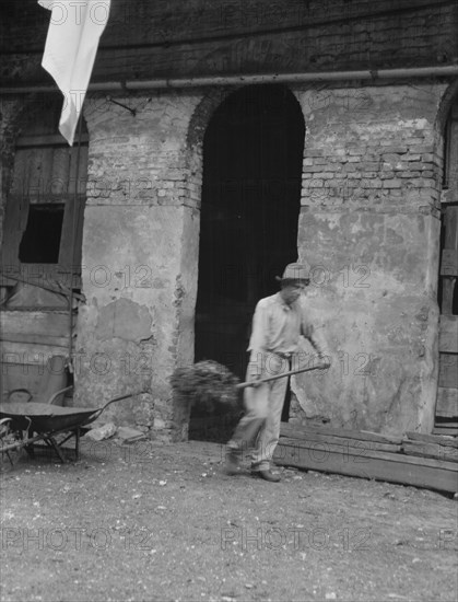 Man cleaning out a small building, New Orleans or Charleston, South Carolina, between 1920 and 1926. Creator: Arnold Genthe.