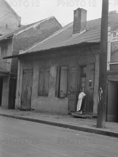 View from across street of a woman standing by a doorway in the French Quarter, New..., c1920-c1926. Creator: Arnold Genthe.