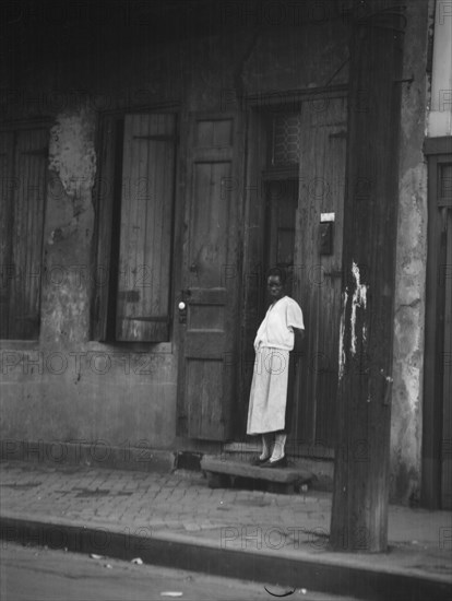 View from across street of a woman standing in a doorway in the French Quarter, New..., c1920-c1926. Creator: Arnold Genthe.