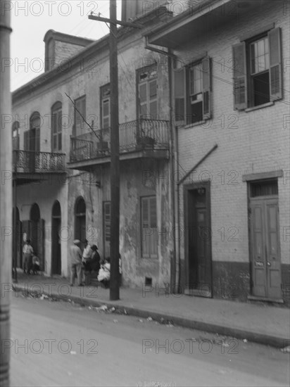 View from across street of four people talking in the French Quarter, New Orleans, c1920-1926. Creator: Arnold Genthe.