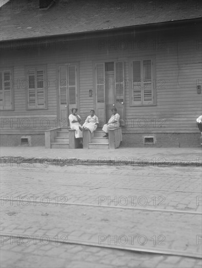 View from across street of three women talking, New Orleans or Charleston, South Ca., c1920-c1926. Creator: Arnold Genthe.