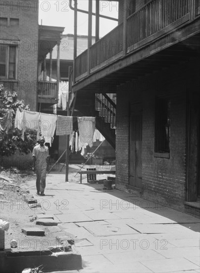 Man standing in a courtyard, New Orleans, between 1920 and 1926. Creator: Arnold Genthe.